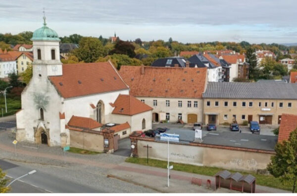 Hof des Hospitalgutes mit Kirche aus der Vogelperspektive. Die städtische Umgebung wird mit gezeigt.