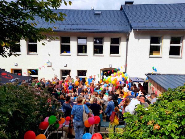 Blick auf Kita mit Kindern und Luftballons