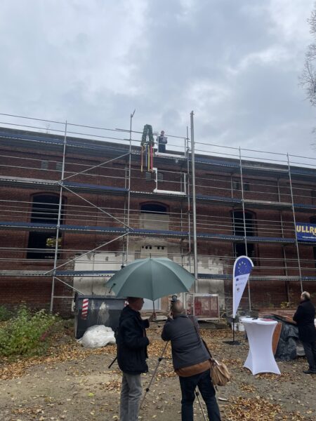 Blick auf eingerüstete Turnhalle mit Richtkranz