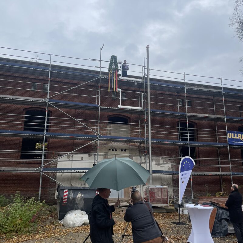 Blick auf eingerüstete Turnhalle mit Richtkranz